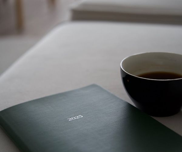 Calendar and a cup of tea on a desk symbolizing a daily routine.
