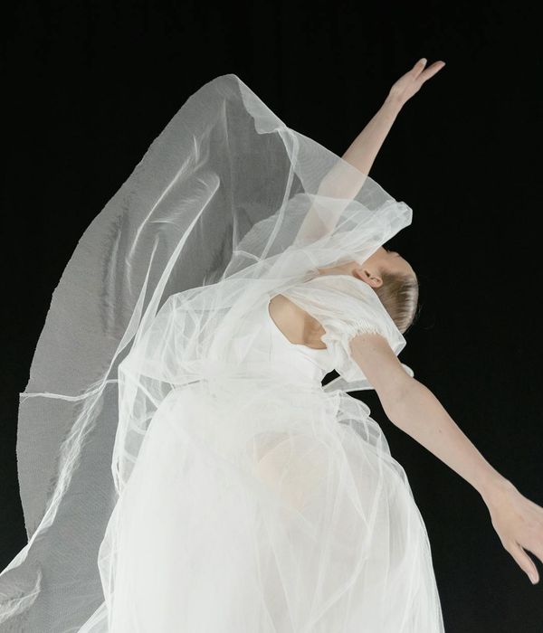 Woman performing a gentle, fluid movement in a bright, airy room.